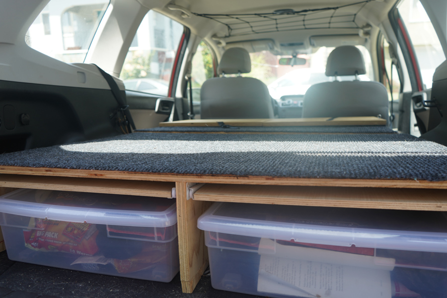 Subaru SUV camper conversion with wooden sleeping platform and drawers 